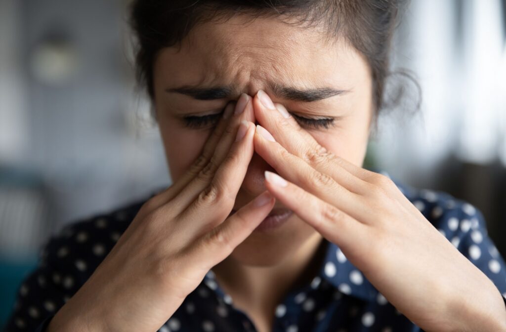 A close-up image of a young adult rubbing their dry eyes in frustration due to irritation.