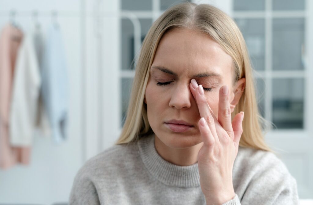 A woman with lupus holding her eyes, uncomfortable due to dry eye symptoms