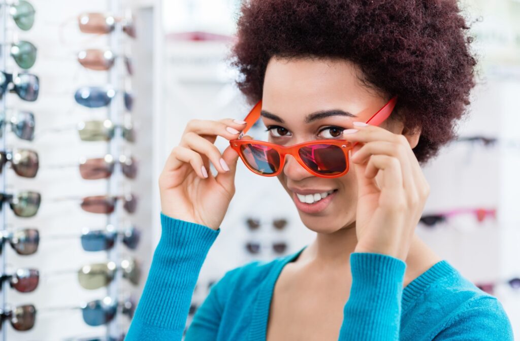 A smiling patient trying on a pair of polarized sunglasses in front of a display.