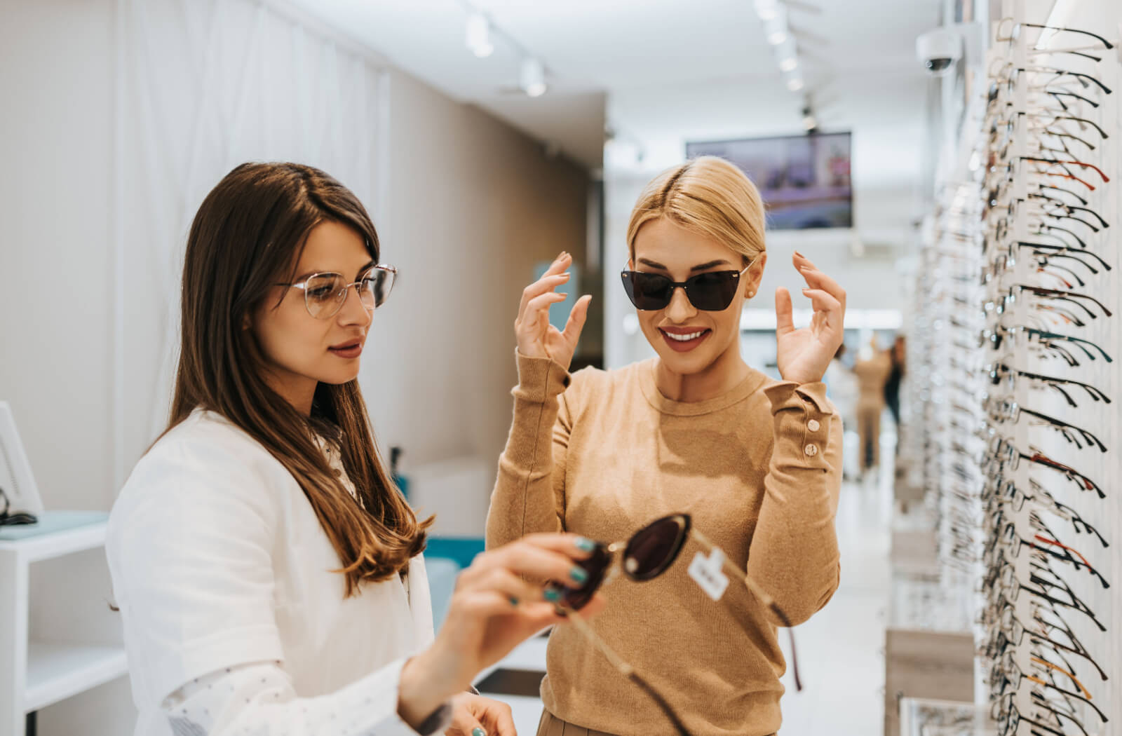 An optometrist helping a patient choose sunglasses from a display to help with their light sensitivity.